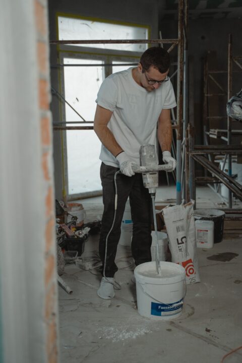 Vakman mengt egaline in een emmer met een mengmachine