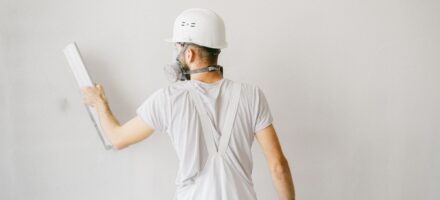 Vakman vlakt een wand af met een spaan